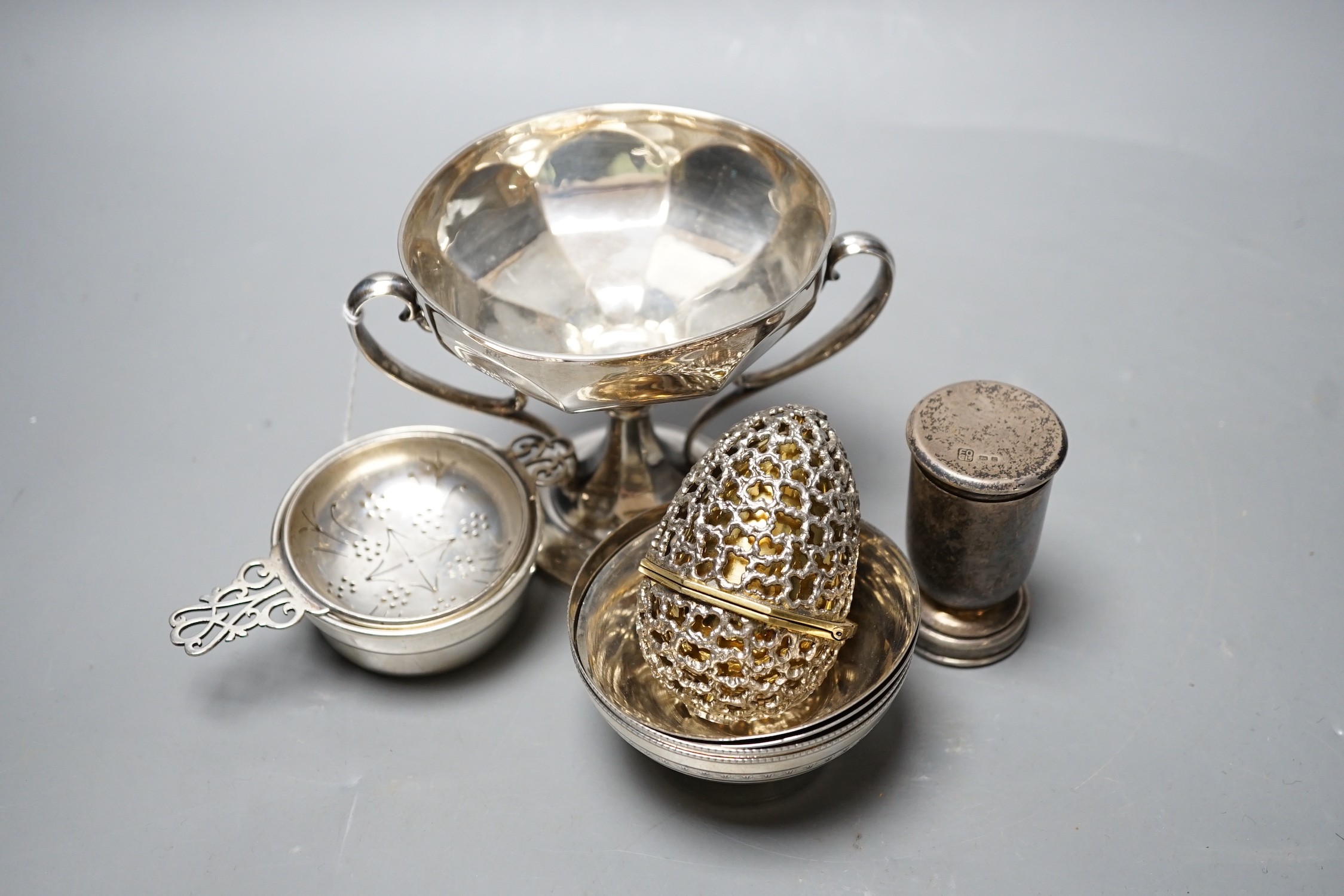 Small silver including Edwardian two handled pedestal bowl, Goldsmiths & Silversmiths Co Ltd, London, 1907, 97mm, a later silver tea strainer on stand, four Egyptian white metal finger bowls, a George VI communion set, L